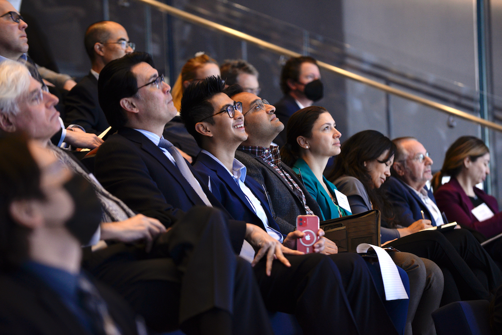 Event attendees in business professional attire, seated with heads tilted back looking up