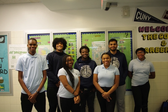 A group of students in uniforms pose for the camera in their school hallway