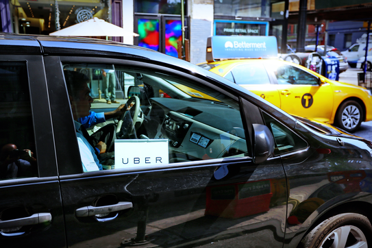 An Uber driver and a taxi in the background
