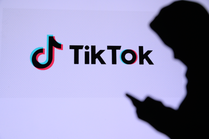 A person using a mobile device next to a TikTok logo